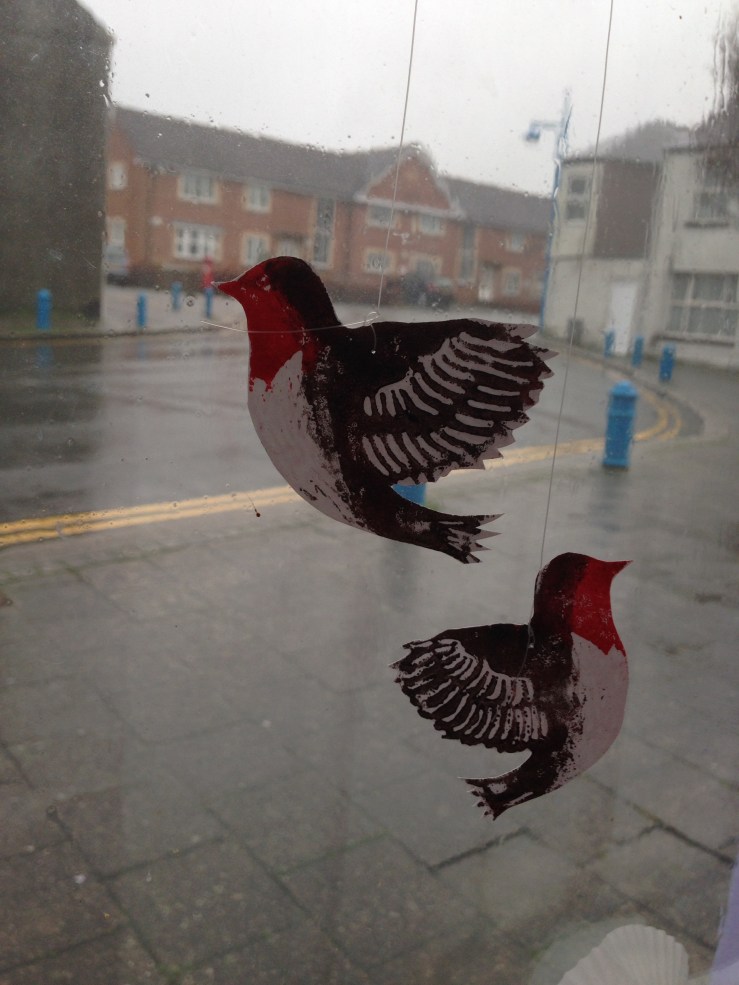 Paper robins displayed in a window.